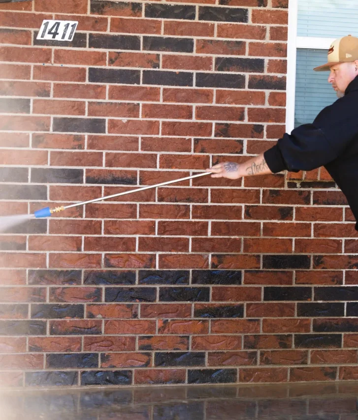 Mighty Waters technician pressure washing a brick exterior
